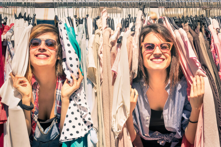 two girls peaking through clothes hanging in closet