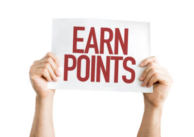 Two hands are proudly holding up a sign with the text EARN POINTS in bold red letters against a pristine white background, offering a visual invitation to supercharge your travel rewards.